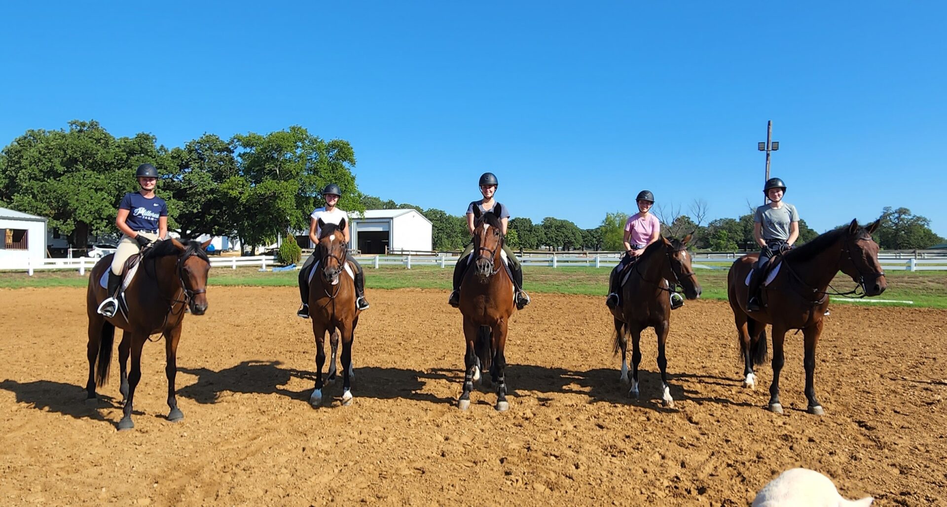 Three people riding horses on a dirt field.